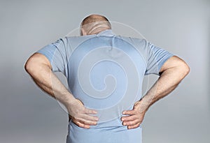Mature man suffering from backache on light background