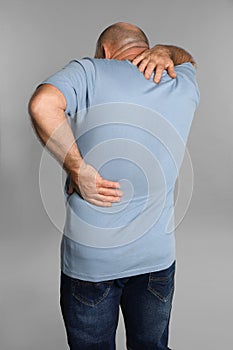 Mature man suffering from backache on light grey