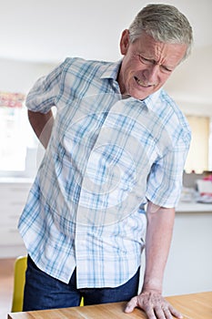 Mature Man Suffering From Backache Whilst Getting Out Of Chair A