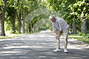 Mature Man Suffering Knee Injury While Walking Outdoors In Park