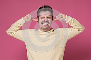 Mature man suffering from loud music and pain trying to plug ears