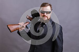 Mature man in sunglasses dressed in suit with tommy gun