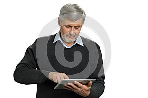 Mature man surfing net on computer tablet.