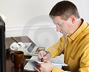 Mature man taking data off the computer for doing income taxes