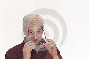 mature man taking off his glasses with both hands and looking straight ahead