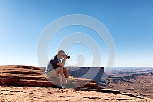 Mature man taking photos of the Grand Canyon while sitting down
