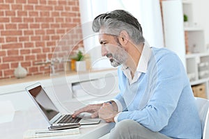 Mature man teleworking on laptop