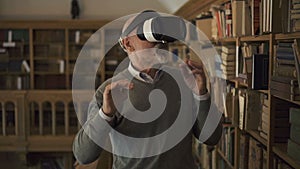 Mature man is testing virtual reality glasses standing in vintage library.