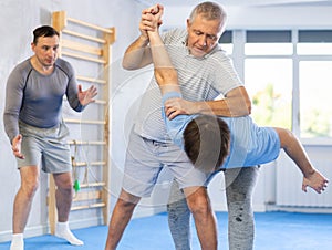 Mature man throws guy to the mat - two men of different ages in judo sparring