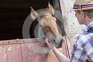 Mature man touching horse at stable in farm