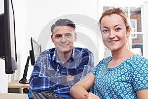 Mature Man Training Young Woman On Computer In Office