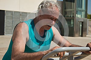 mature man trying hard training on the street with sports machine
