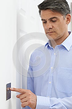 Mature Man Turning Off Light Switch At Home