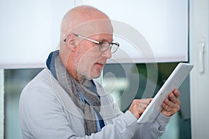 Mature man using digital tablet at home