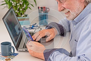 Mature man using laptop computer and mobile phone at home, Businessman working in office.Freelance, studying, technology online