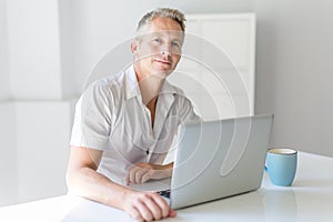 Mature Man Using Laptop On Desk At Home