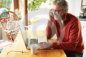 Mature Man Using Mobile Phone And Laptop