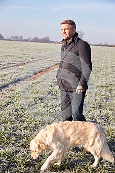 Mature Man Walking Dog In Frosty Landscape