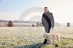 Mature Man Walking Dog In Frosty Landscape