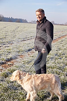 Mature Man Walking Dog In Frosty Landscape