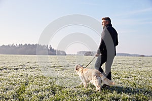 Mature Man Walking Dog In Frosty Landscape