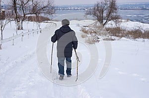 Man walking on a snowy road down to frozen Dnipro river in Ukraine