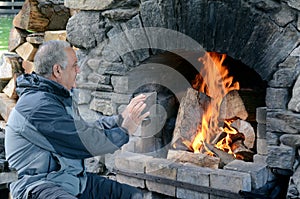 Mature man warm up with fireplace