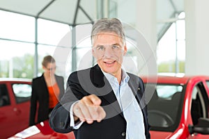 Mature man with woman and auto in car dealership