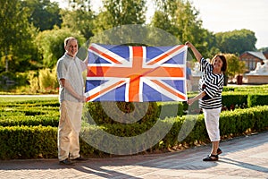 Mature man and woman holding british flag.