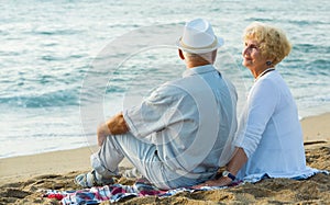 Mature man and woman sitting back on towel