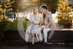 Mature man and woman sitting at park, have business meeting