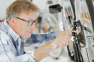 Mature man working on bicycle in workshop
