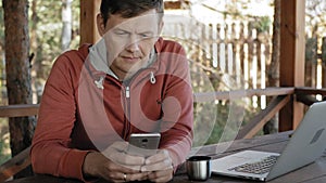 Mature man is working on his laptop outdoors in nature during his vocation aged forester using his laptop for e-mail