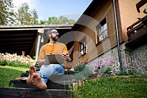 Mature man working outdoors in garden, home office concept.