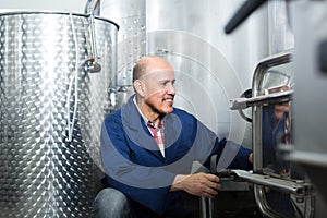 mature man working in wine fermentation section.