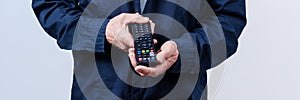 Mature man with wrinkled hands holding tv remote control