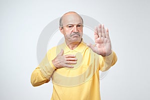 Mature man in yelloe tshirt showing sign stop with hand.