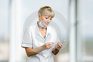 Mature medical female doctor looking on thermometer.