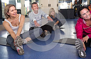 Mature men and women are engaged on mat in gym