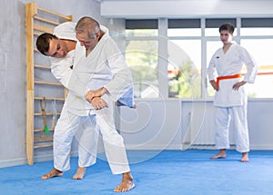 Mature men working on martial arts techniques and maneuvers in training fight