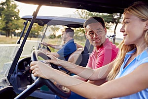 Mature And Mid Adult Couples Driving Buggies Playing Round On Golf Together