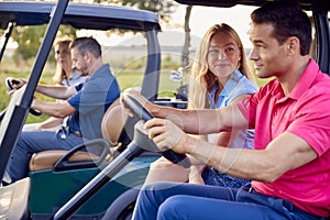 Mature And Mid Adult Couples Driving Buggies Playing Round On Golf Together