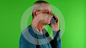 Mature mid aged man talking on a phone. Portrait of a mature white man texting in front of green screen.