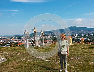 A mature middle-aged woman with blond hair stands in front of an observation deck on Mount Calvaria in the city of Nitra in photo