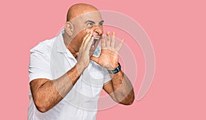 Mature middle east man with mustache wearing casual white shirt shouting angry out loud with hands over mouth