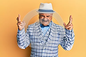 Mature middle east man with mustache wearing vintage and elegant fashion style gesturing finger crossed smiling with hope and eyes