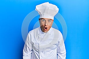 Mature middle east man wearing professional cook uniform and hat afraid and shocked with surprise expression, fear and excited