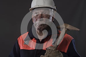 Mature miner covered in coal dust holding a pick axe