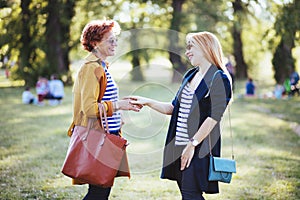 Mature mother and adult daughter enjoying in the park