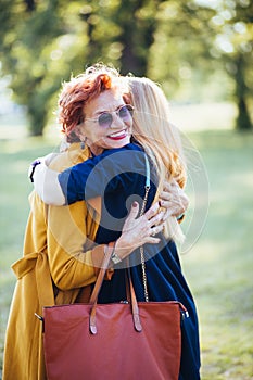 Mature mother and adult daughter hugging in the park